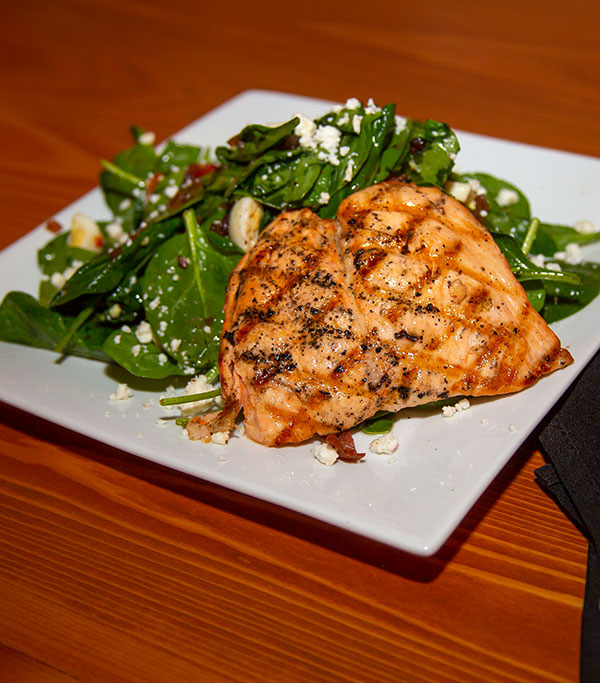 Grilled salmon adds protein to a delicious spinach salad with goat cheese, marinated portabella, roasted red peppers and crispy pancetta tossed in a warm bacon balsamic dressing.