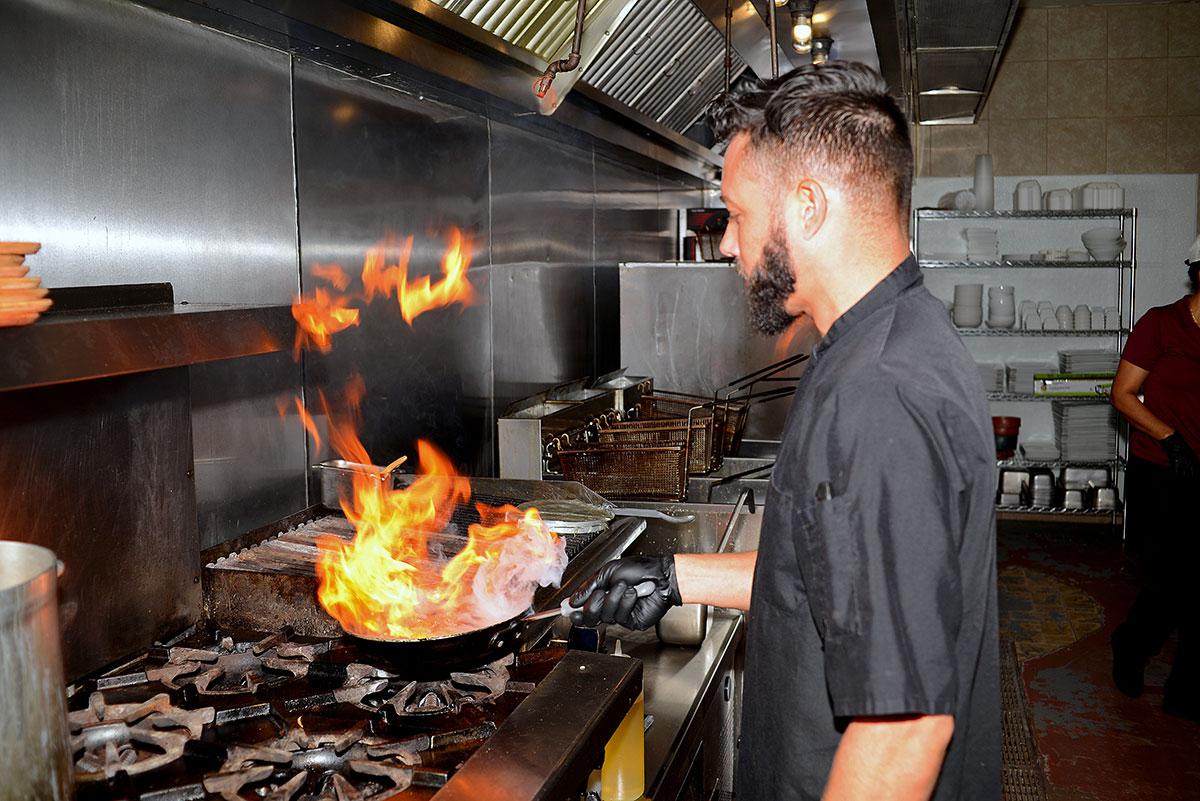 Chef Manuel Acevedo puts flame to one of Dom Rico’s specialties, a churrasco, grilled skirt steak, with chimichurri in the open-air kitchen.