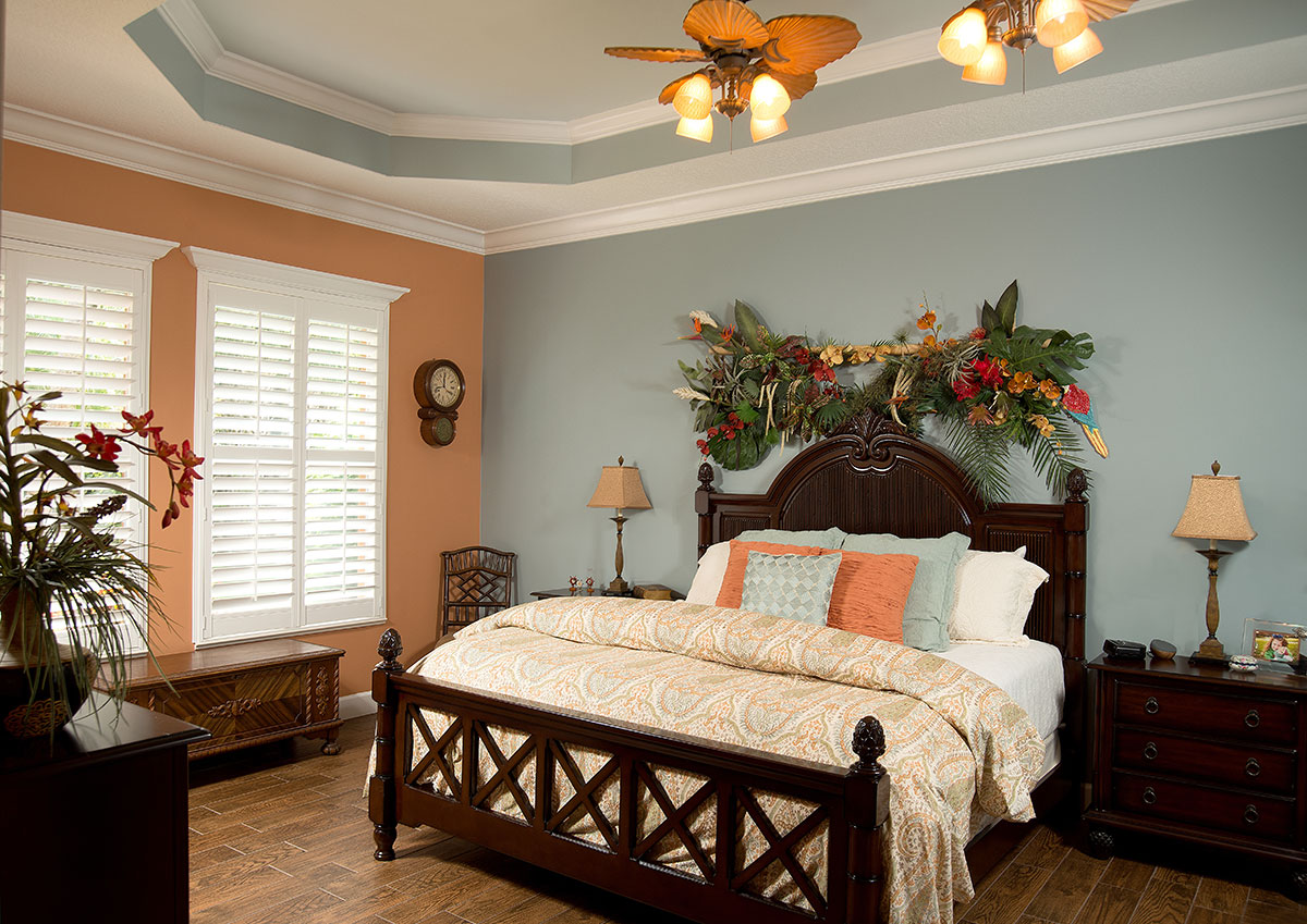 Two ceiling fans cool the master bedroom with its mixed paint scheme, crown molding and a coffered ceiling painted to look like the sky.