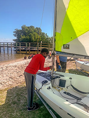 A youngster prepares his sailboat before taking the tiller