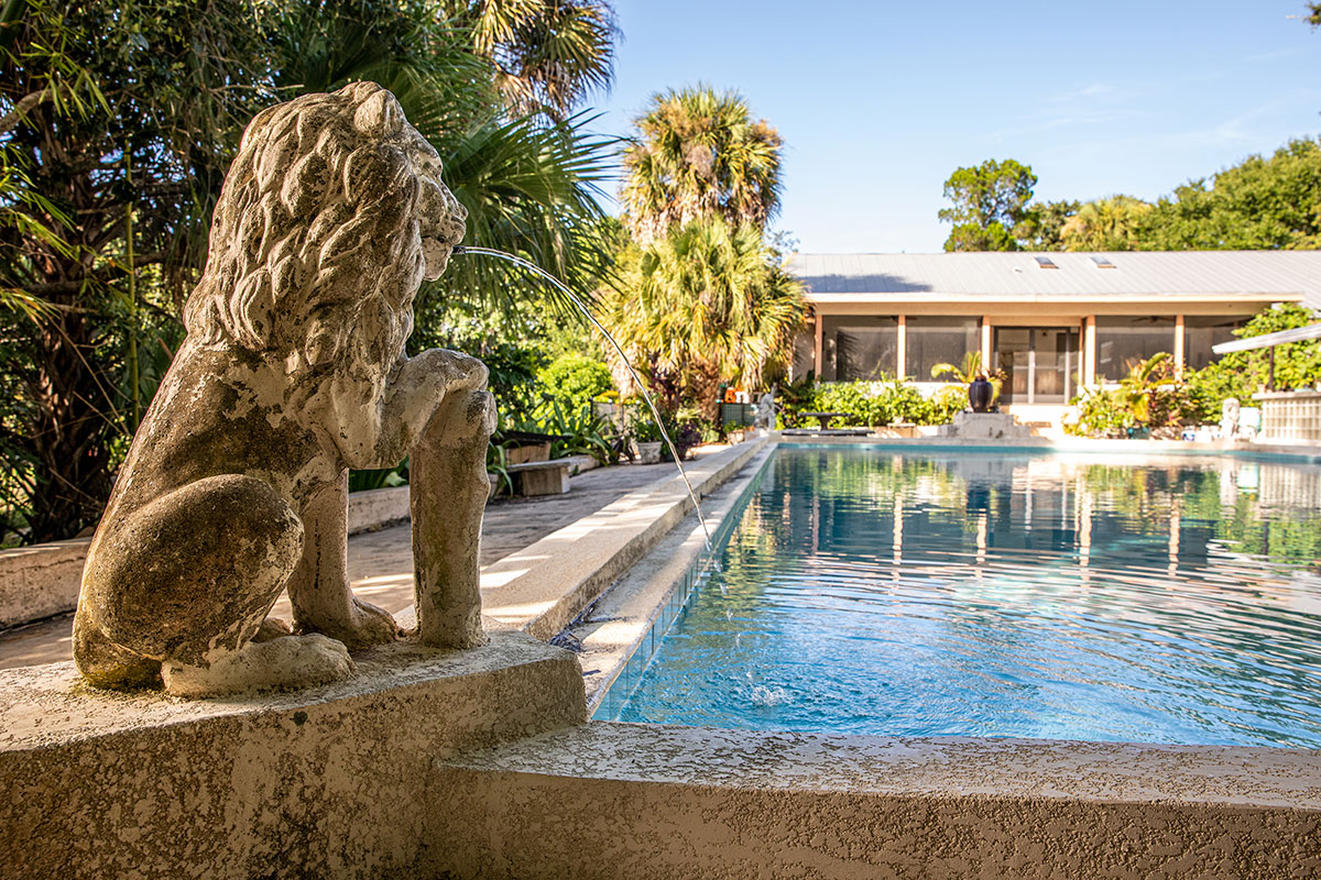 Statues of lions stand at each corner of the Art Deco style swimming pool
