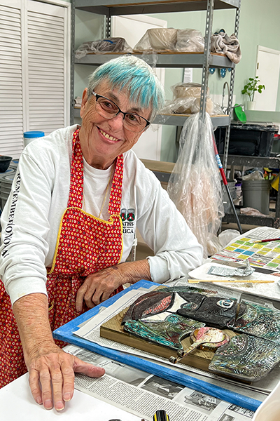Charley Moses is working on her Raku-fired abstract piece assembled with mixed-media elements.
