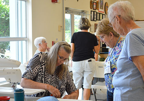 Quilt Show Committee Chair Marian McCoin assists members Donna Bricknell and Pat Neilson with a quilting project.