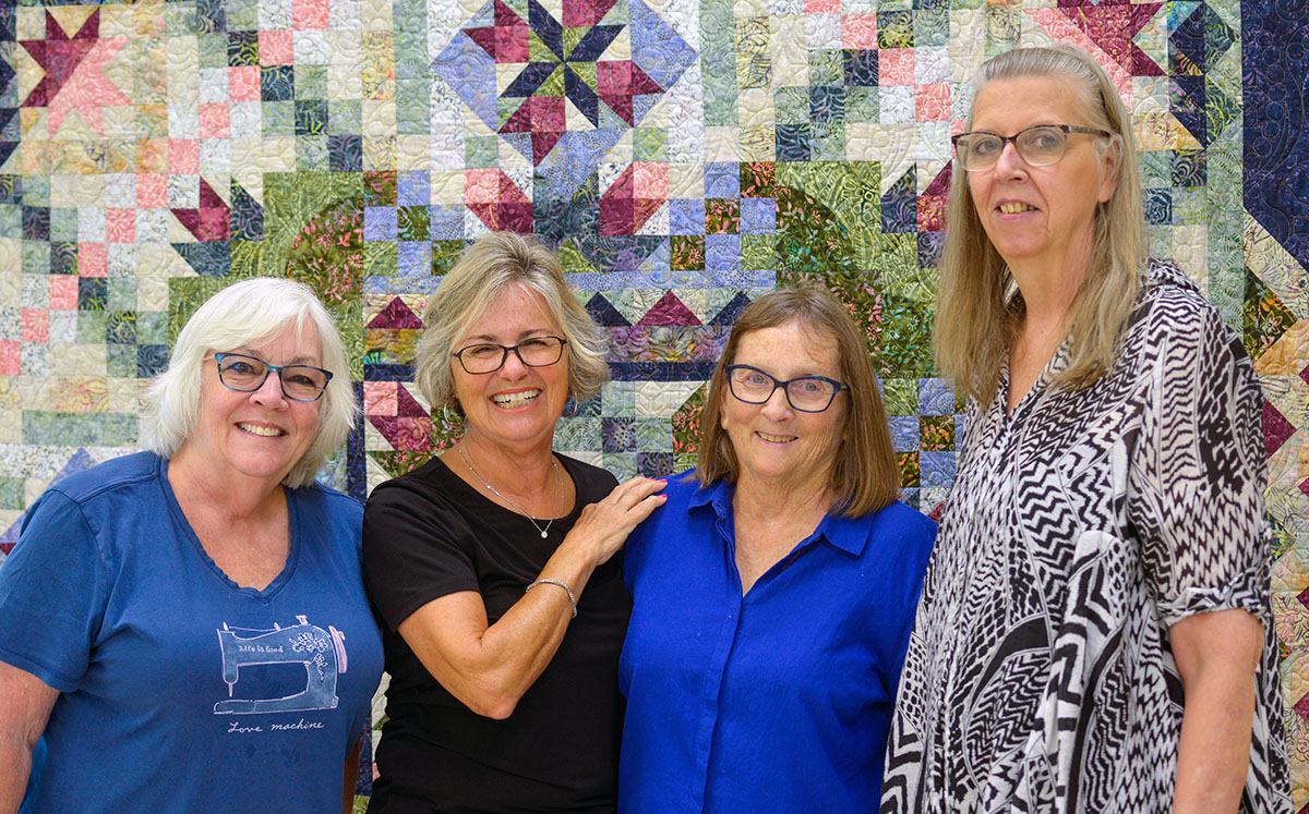 Showing the 2024 Opportunity Quilt that will be raffled off at their biennial quilt show are, from left, Trish Harrison, webmaster; Smiley, president; PauletteLacroix, philanthropy chair; and McCoin, quilt show chair. The quilt was pieced by Cathy Landon and quilted by McCoin.