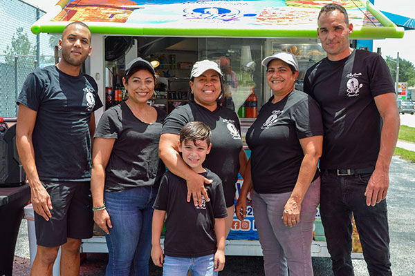 Employees Roberto Ortiz, Daysi Rivera, Luz M. Marquez and Mike Amador flank Oquendo and her grandson, Kaiden Cumba, at the El Hay Bendito food truck. Oquendo says her employees have helped make her food service business a success in Port St. Lucie.