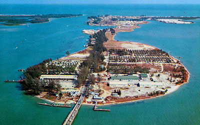 In this 1956 aerial photo of South Beach, Causeway Mobile Home Park is visible among the Australian pine trees in the middle right section of the postcard. In the foreground of this photo are some World War II-era buildings constructed by the U.S. Navy, which used the island to house a frogmen training base during the war. After the war had ended, 
the Navy turned the property and the buildings 
over to the Fort Pierce community.