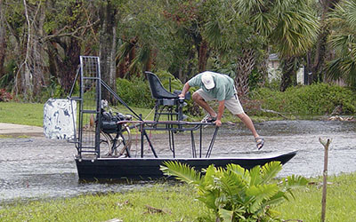 A man gets his airboat ready to navigate the flood after a hurricane. Airboats skim along the surface of the water. 